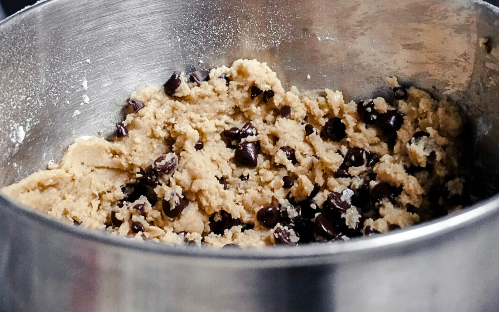Massa de cookie com gotas de chocolate recém-misturada em tigela de inox
