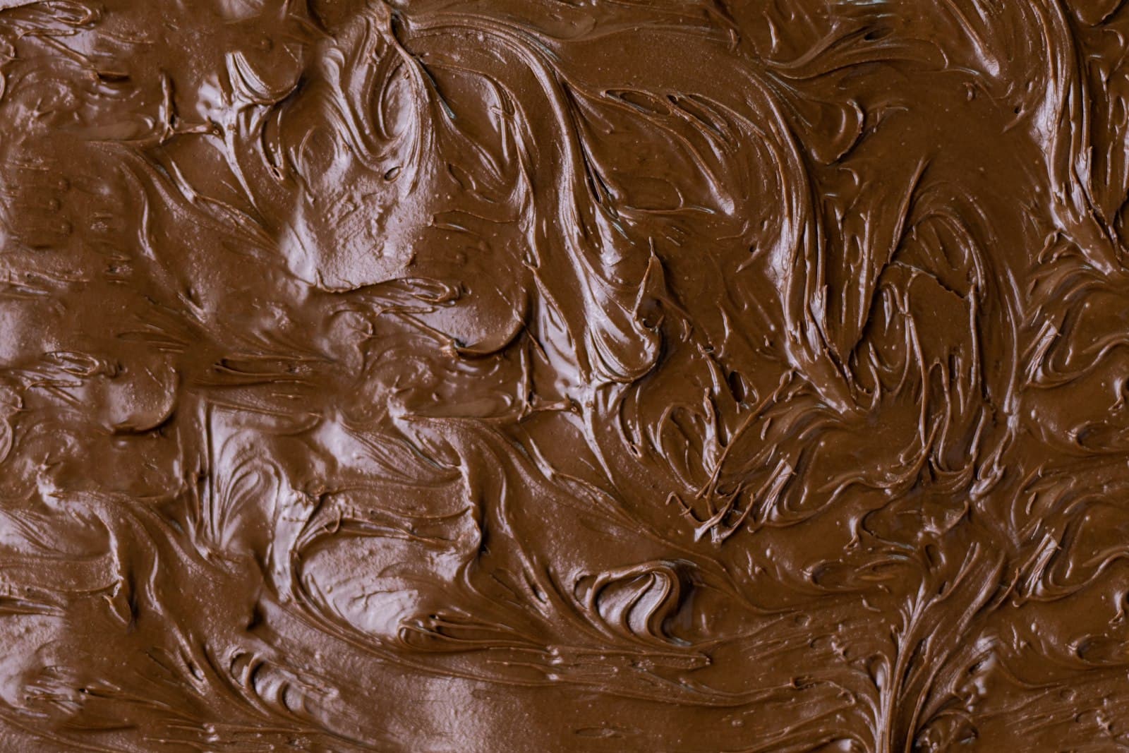 Chocolate derretido sendo espalhado em movimentos circulares sobre uma superfície